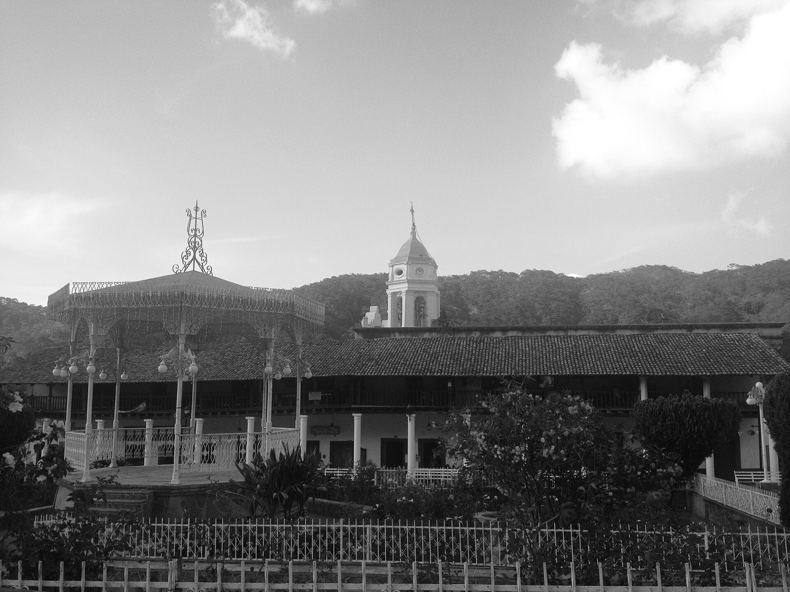 Black-and-white photo of the San Sebastián del Oeste plaza with its gazebo, arcades and church tower