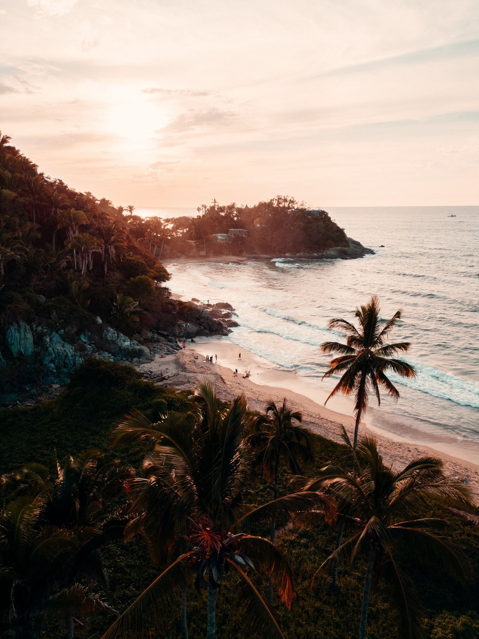 Aerial sunset view of the coastline at San Francisco, Nayarit, with palm trees, rocks and a small beach