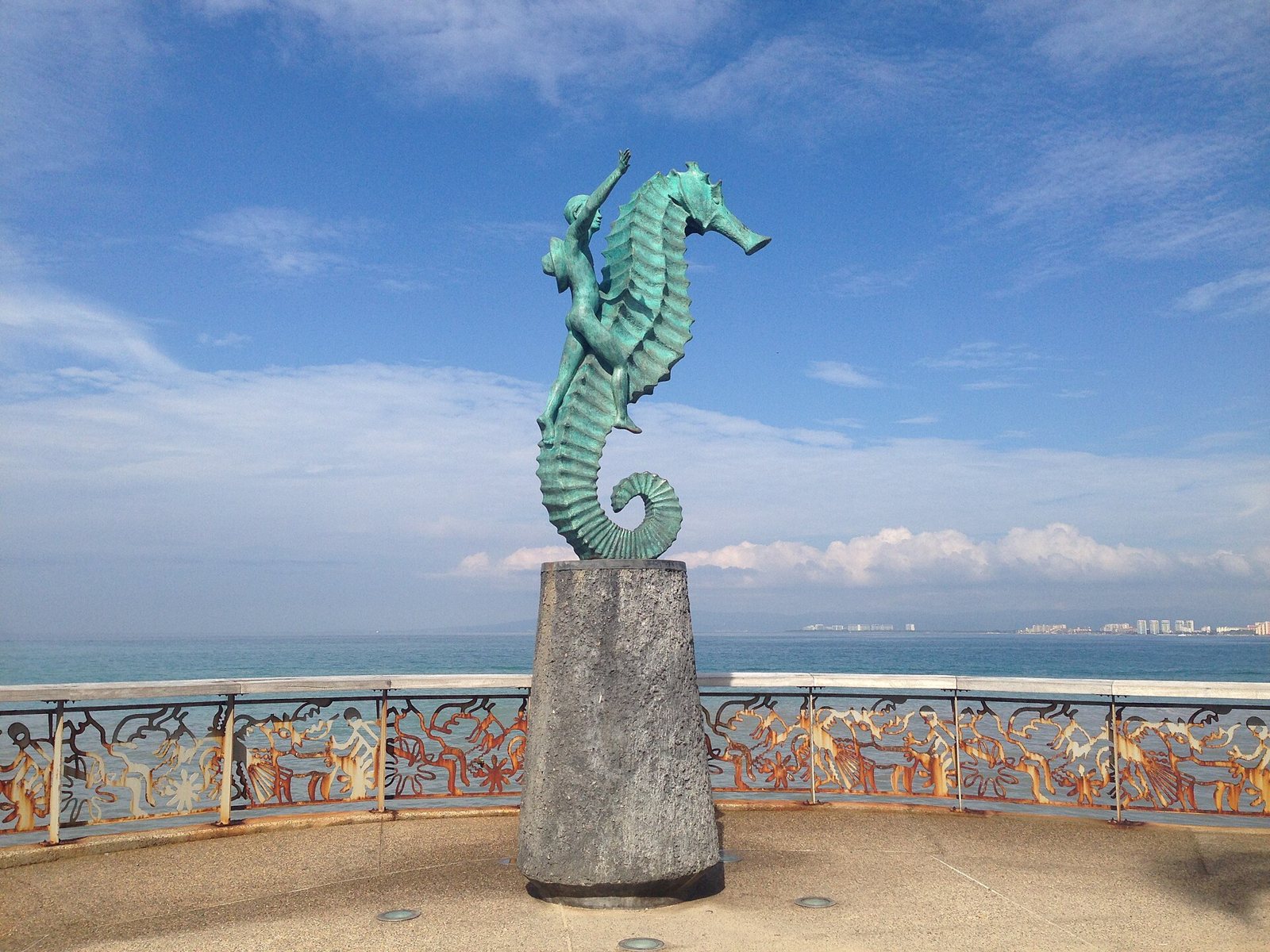 Bronze sculpture of a boy riding a seahorse on the Malecón, with Banderas Bay behind it