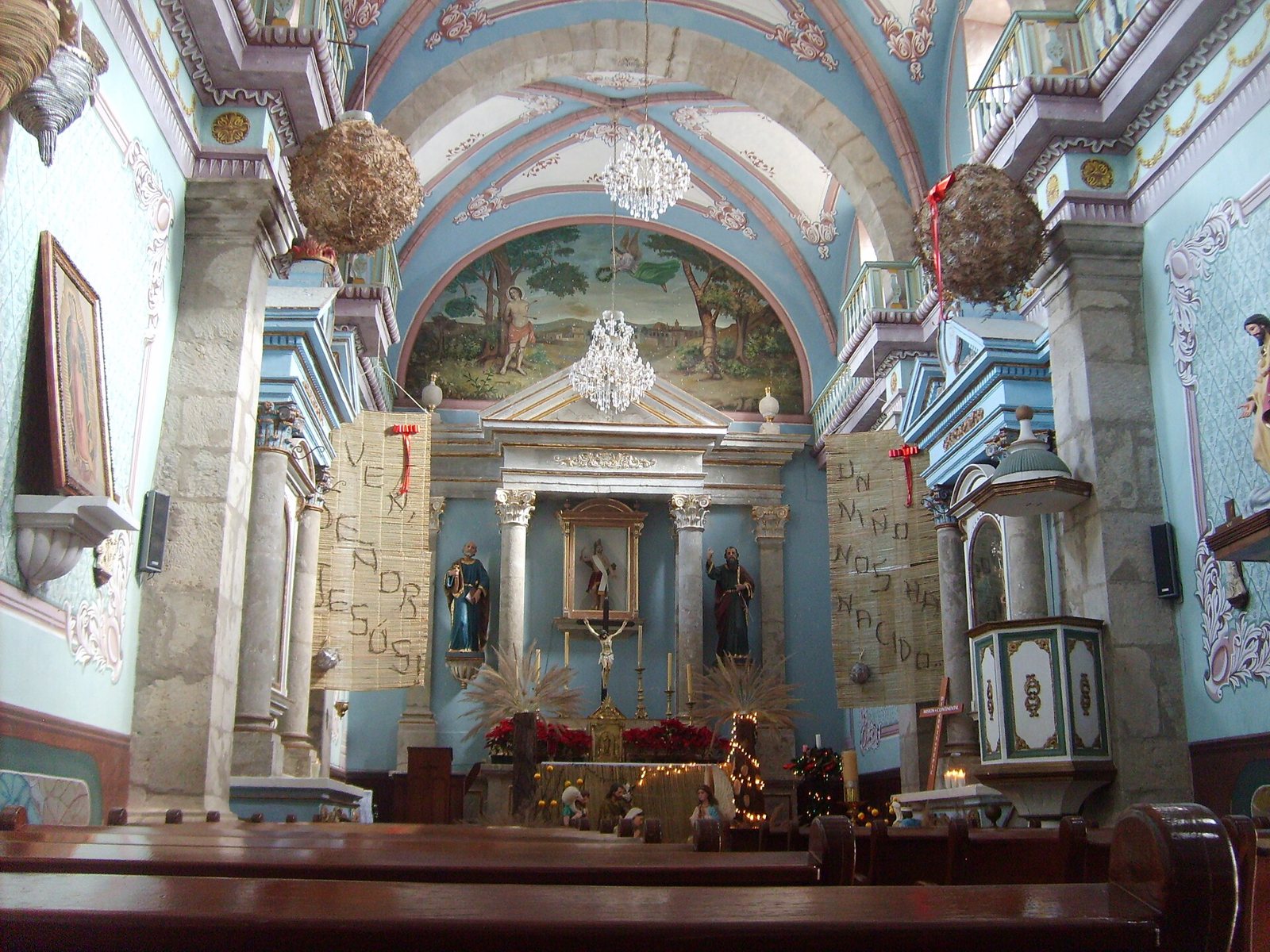 Interior of the San Sebastián church with a painted vault, chandeliers and main altarpiece