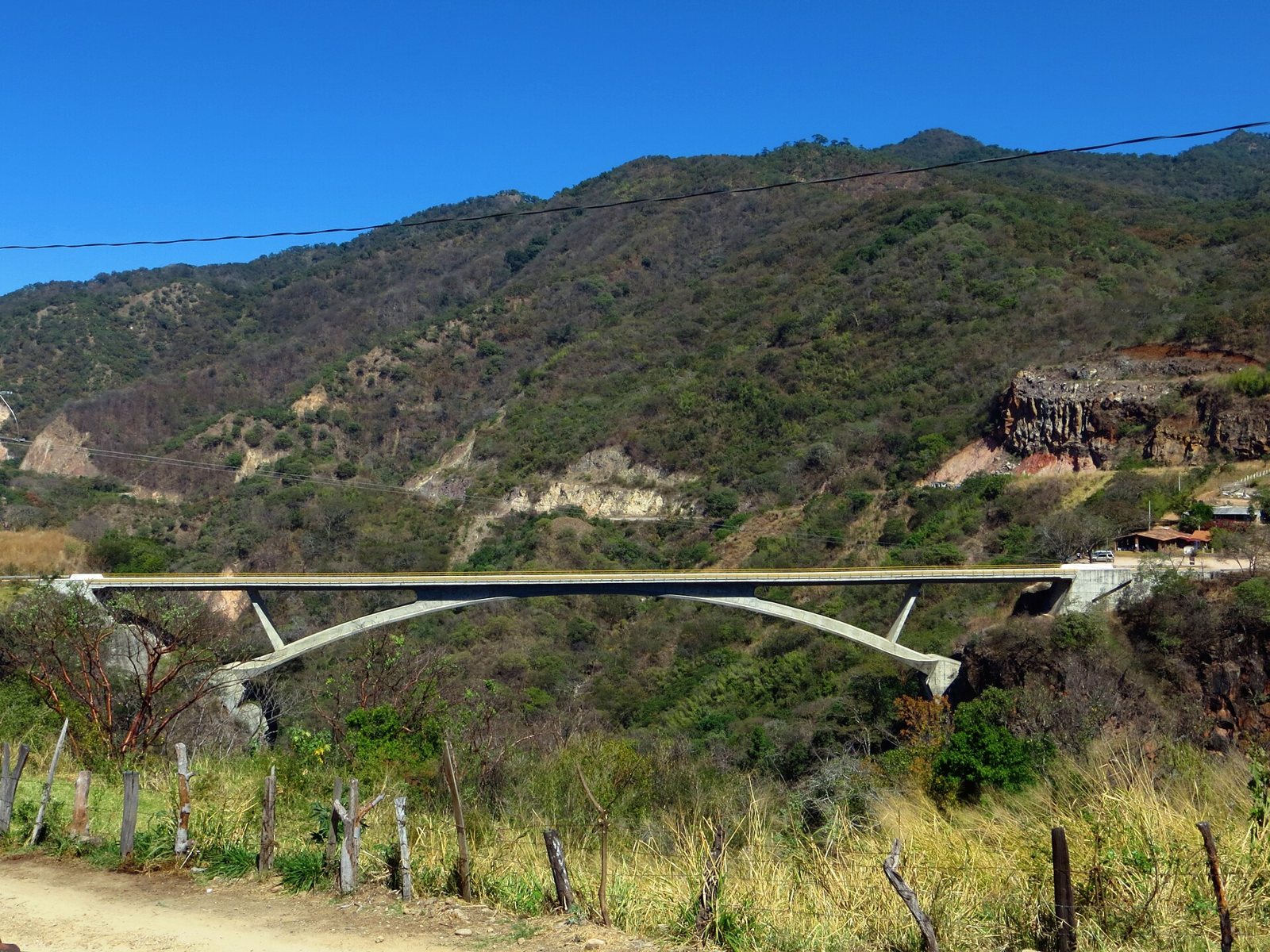 Concrete arch bridge crossing a ravine between forested hills