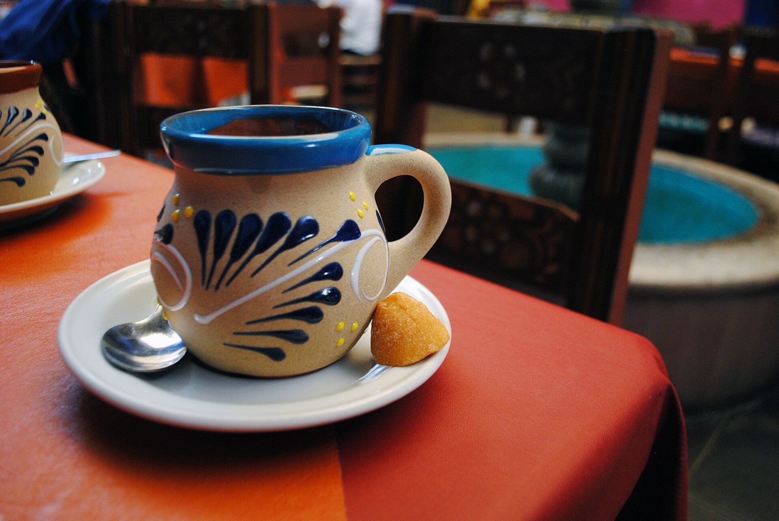 Painted clay mug of coffee on a saucer with a spoon and a piece of piloncillo