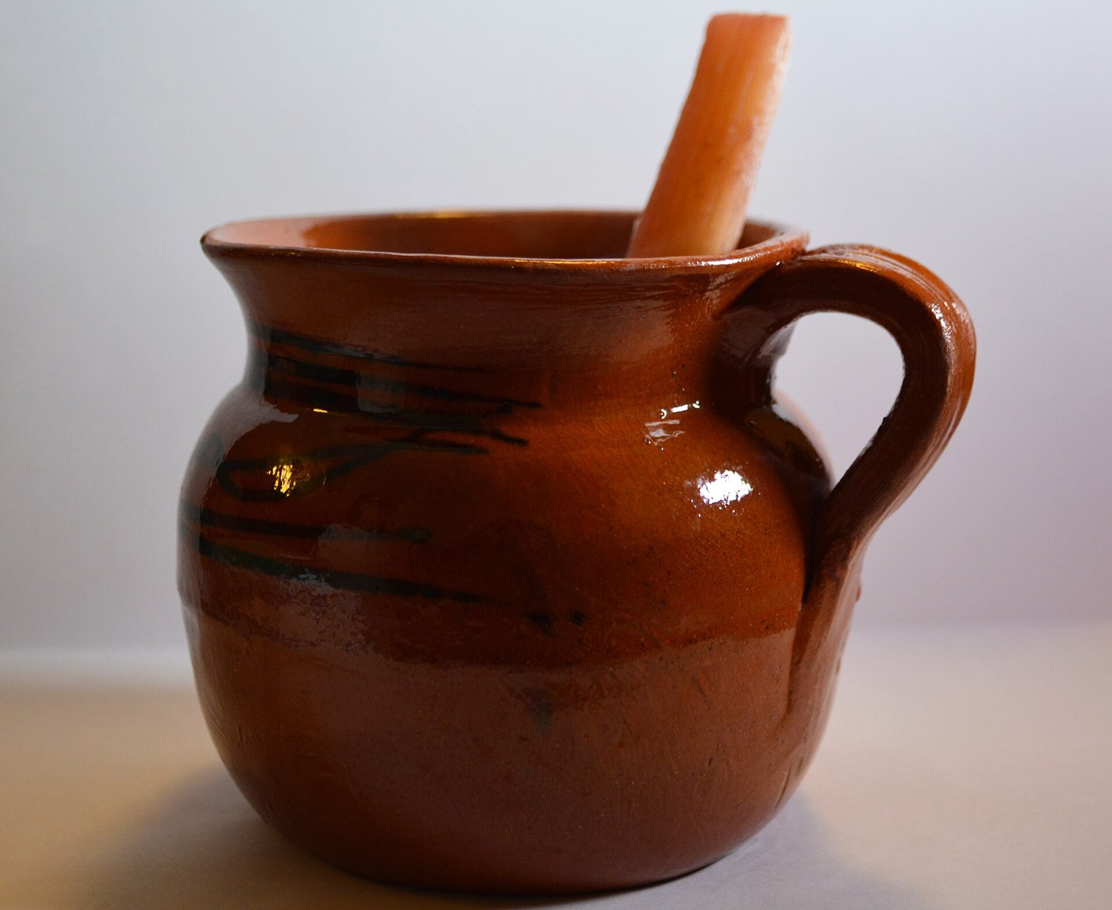 Glazed clay mug of Mexican fruit punch with a stick of sugarcane