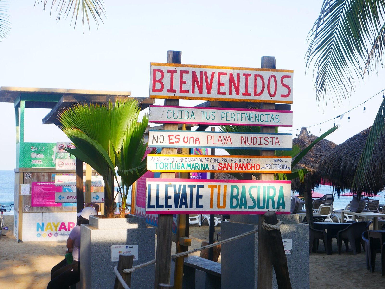 Hand-painted welcome sign at San Pancho beach in Spanish, asking visitors to watch their belongings, protect sea turtles and take their trash with them