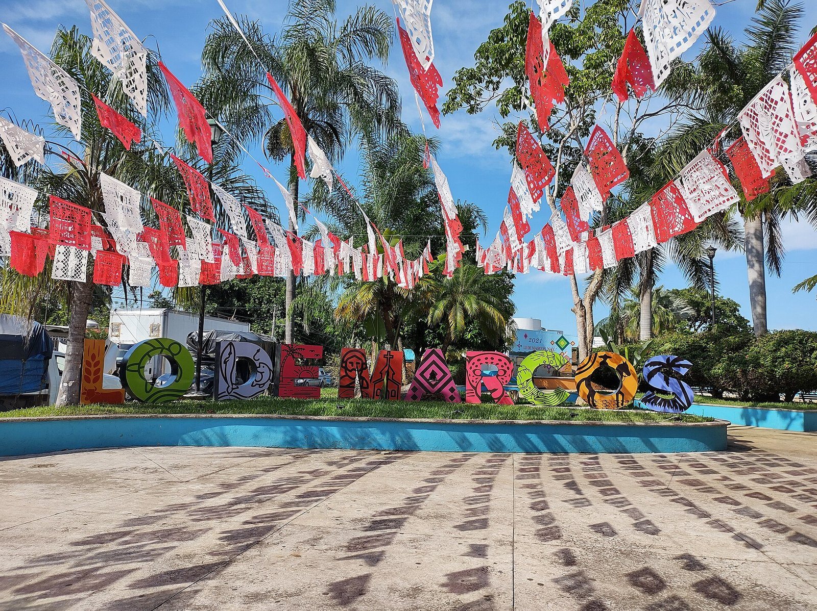 Colorful Lo de Marcos letters in the town plaza under papel picado banners