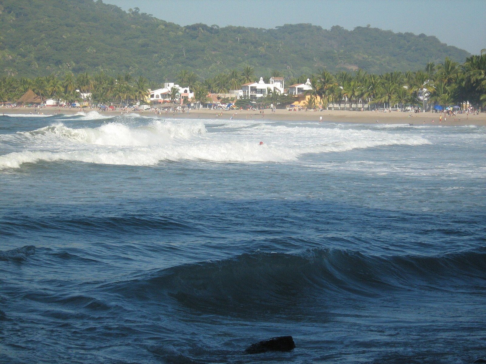 Waves in the Lo de Marcos bay with the town and green hills behind