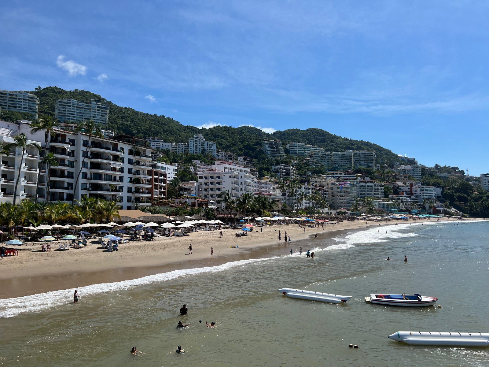 Los Muertos Beach seen from the pier, with buildings and green hills behind