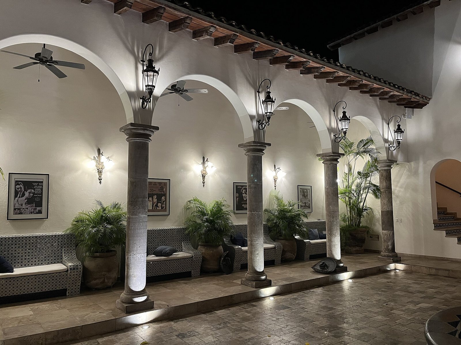 Arched stone-column portico lit at night with potted palms at Casa Kimberly