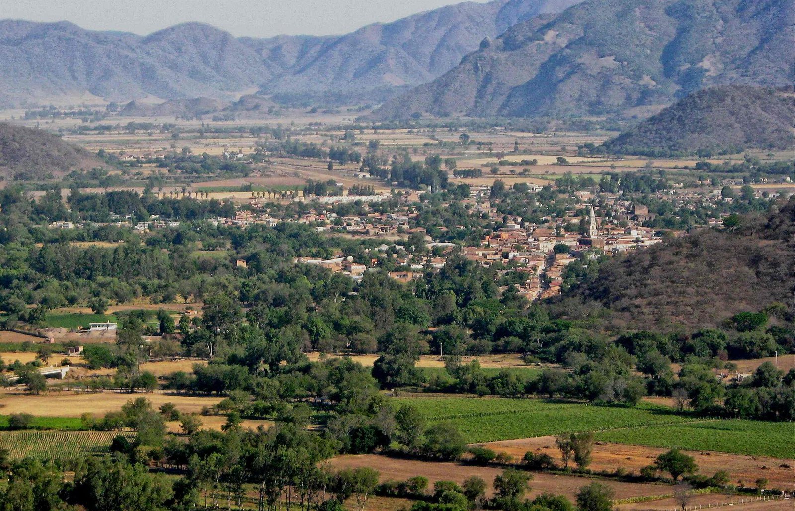 Wide view of the Mascota valley with farm fields, the town in the distance and the Sierra Madre mountains behind