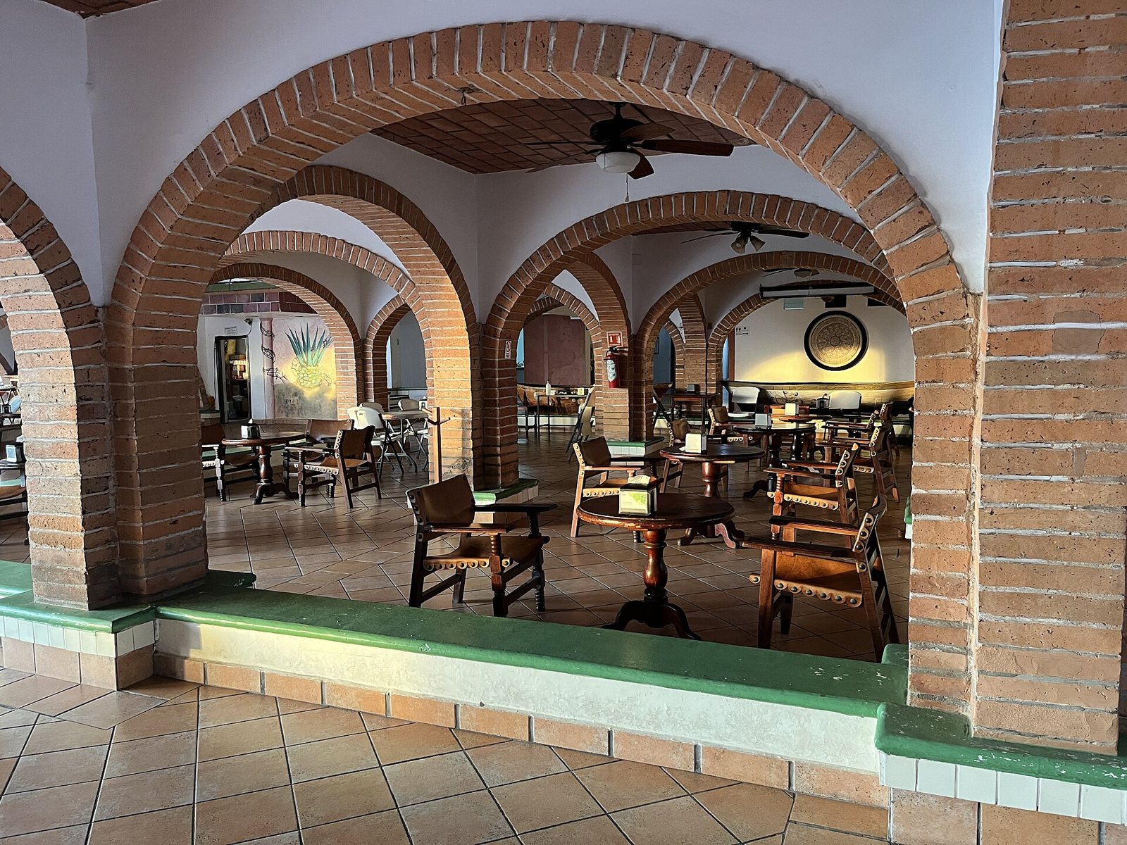 Exposed brick arches over wooden and leather tables and chairs in a covered area of Hotel Rosita