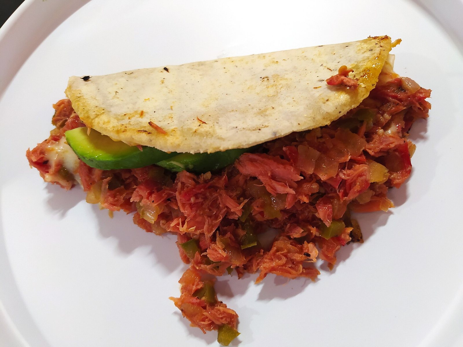 Corn tortilla quesadilla filled with marlin stewed with tomato and peppers, with a slice of avocado