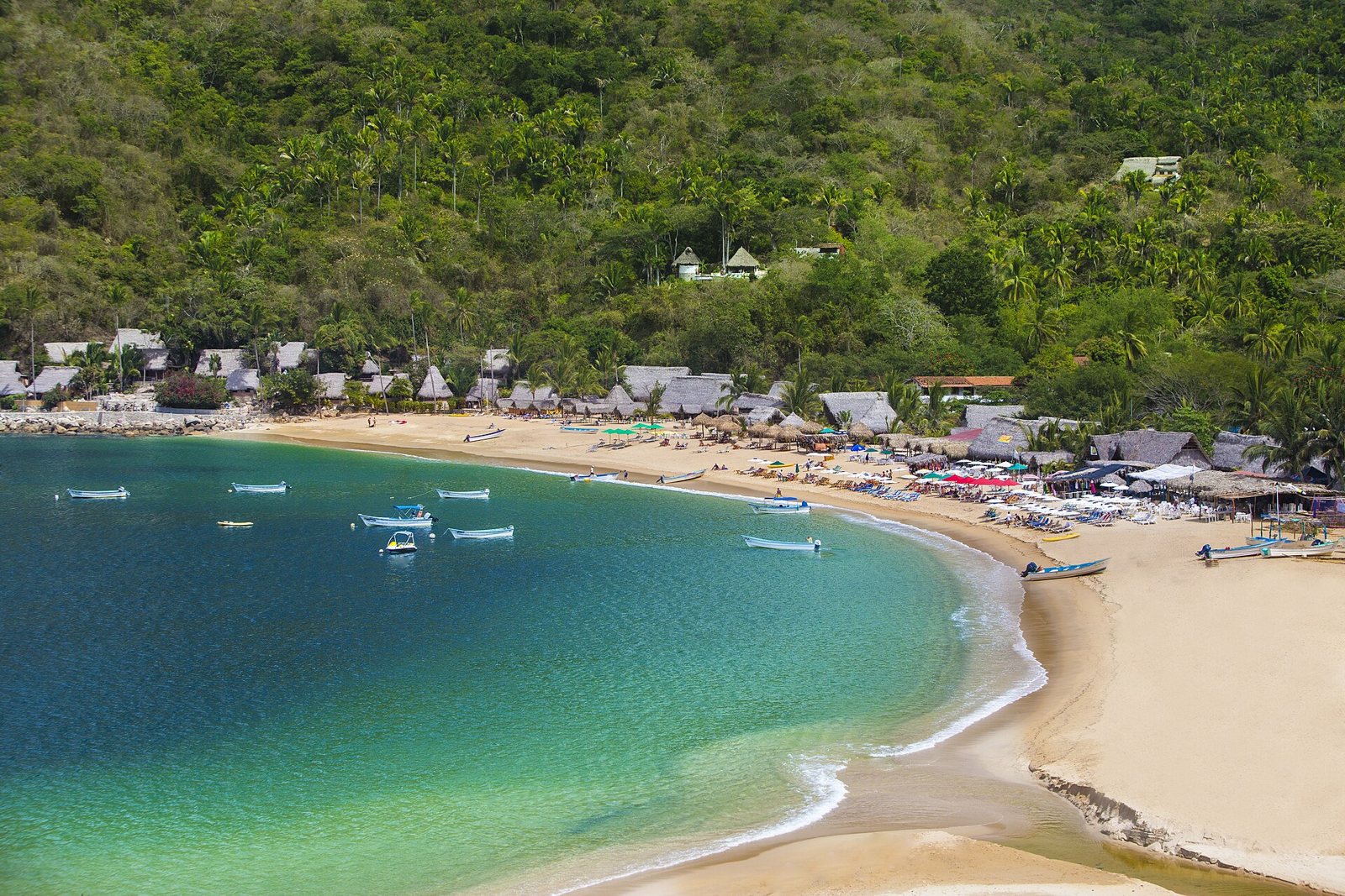 High view of Yelapa beach with turquoise water, moored pangas, thatched palapas and palm-covered hills